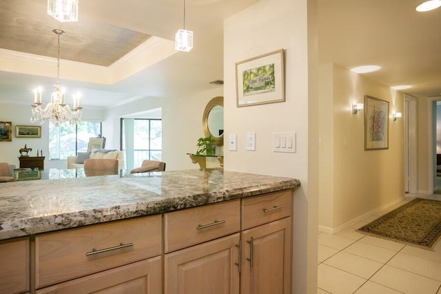 kitchen with light tile patterned floors, hanging light fixtures, light stone countertops, and a raised ceiling