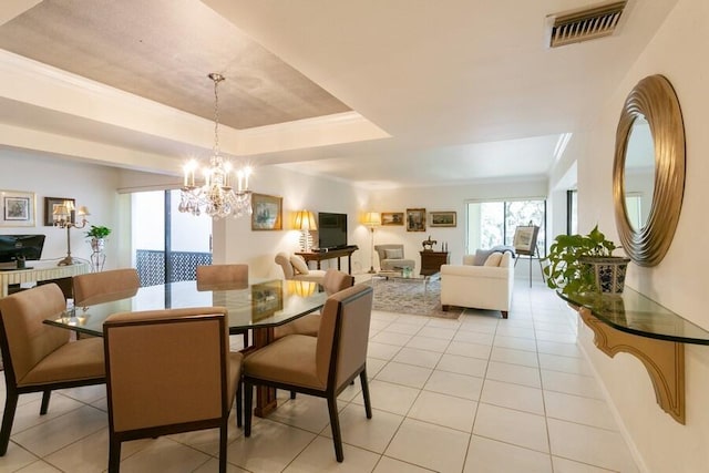 dining area with a chandelier, light tile patterned floors, a raised ceiling, and crown molding