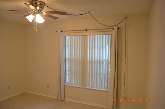 unfurnished room with ceiling fan and a textured ceiling