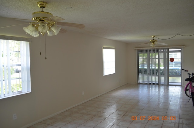 tiled spare room with ceiling fan and a textured ceiling