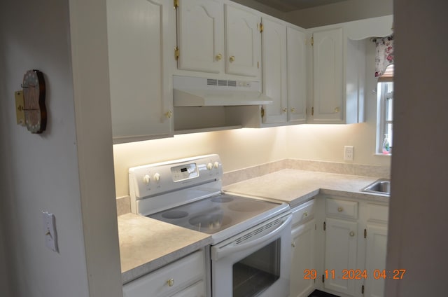 kitchen featuring electric stove, white cabinetry, and sink