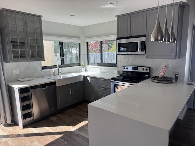 kitchen featuring gray cabinetry, pendant lighting, sink, dark hardwood / wood-style floors, and stainless steel appliances