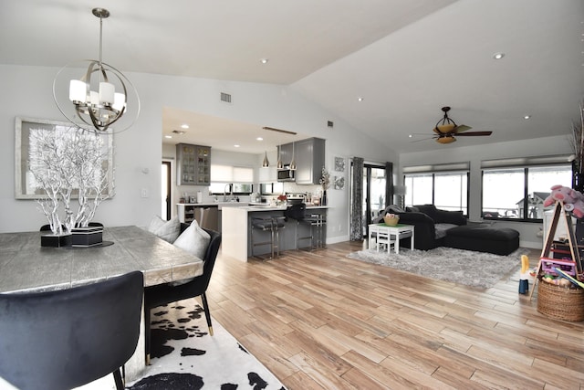 dining space with ceiling fan with notable chandelier, lofted ceiling, and sink