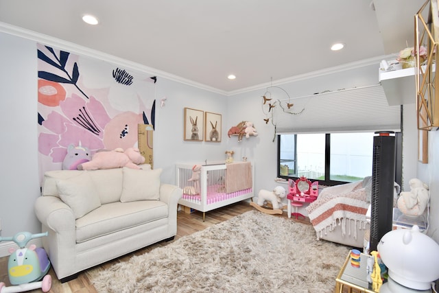 bedroom featuring hardwood / wood-style floors, a crib, and ornamental molding