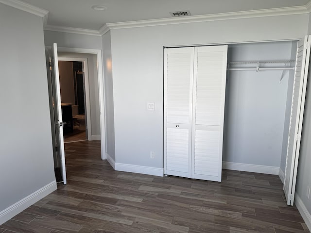 unfurnished bedroom with dark hardwood / wood-style floors, a closet, and crown molding