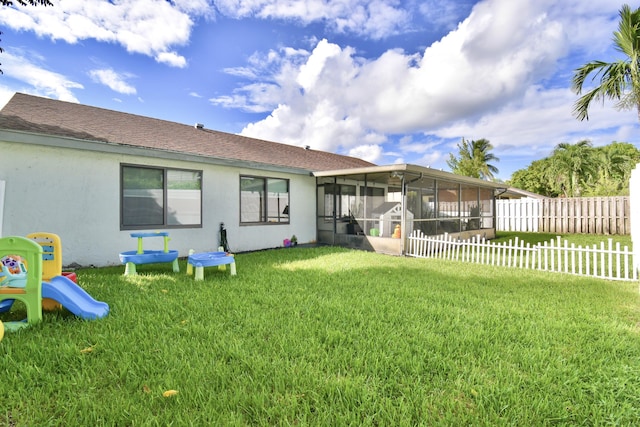 rear view of property featuring a lawn and a sunroom