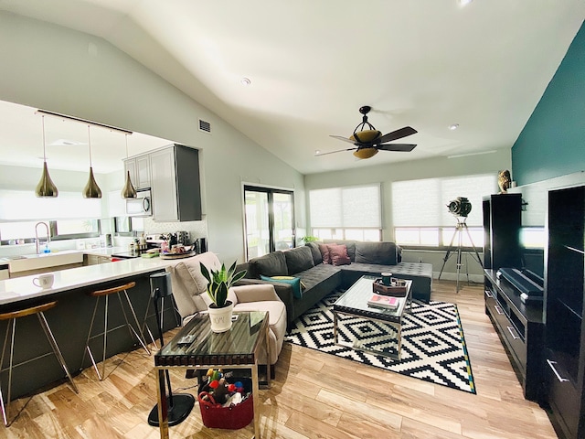 living room featuring light wood-type flooring, ceiling fan, lofted ceiling, and sink