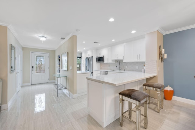 kitchen with a kitchen bar, kitchen peninsula, white cabinetry, and stainless steel appliances