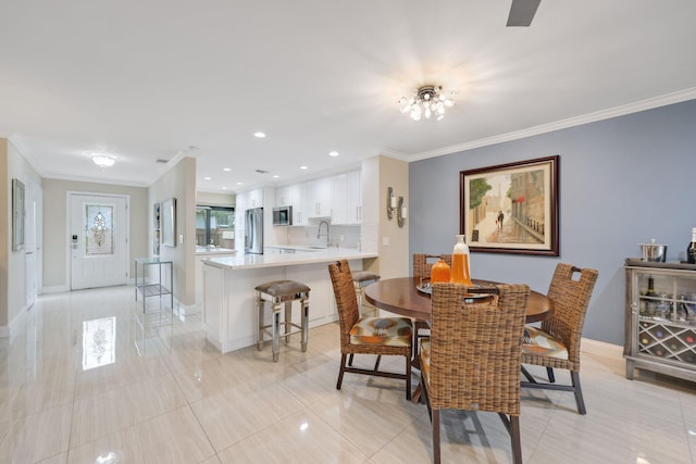 dining room with sink, light tile patterned floors, and ornamental molding