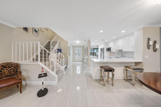 kitchen featuring kitchen peninsula, tasteful backsplash, stainless steel appliances, sink, and white cabinetry