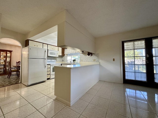 kitchen with white cabinetry, kitchen peninsula, white appliances, decorative backsplash, and light tile patterned floors