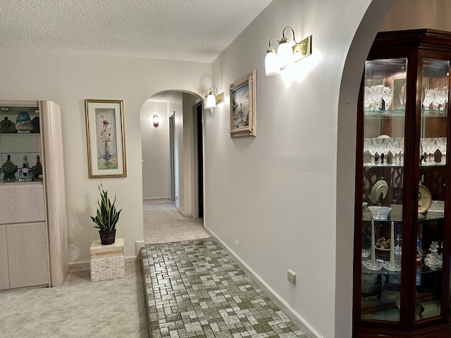 hall with carpet flooring and a textured ceiling