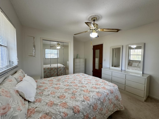 carpeted bedroom with ceiling fan, multiple windows, a textured ceiling, and a closet