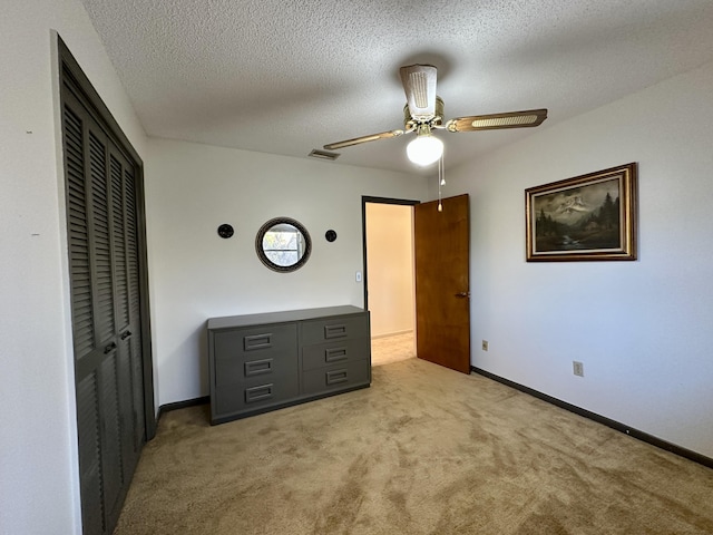 unfurnished bedroom with ceiling fan, a textured ceiling, and light carpet