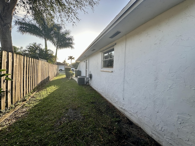 view of home's exterior with central air condition unit and a lawn