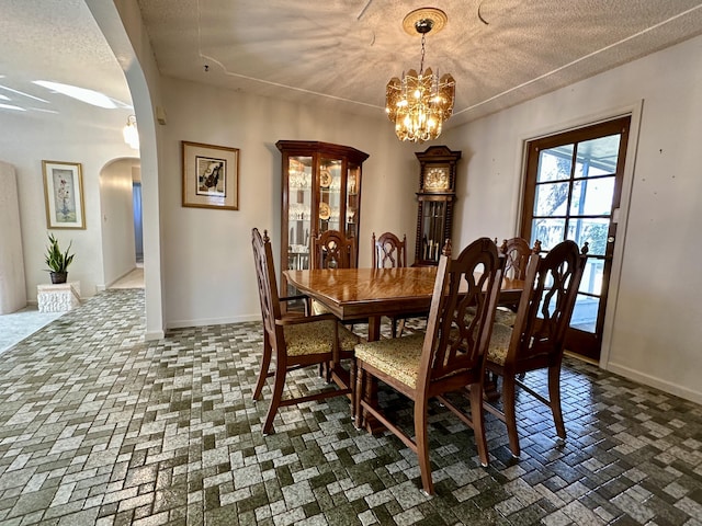 dining space with a textured ceiling and an inviting chandelier