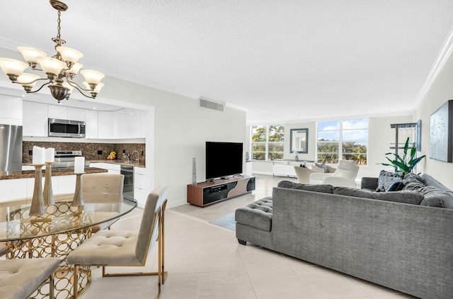 living room featuring a chandelier, light tile patterned floors, a textured ceiling, and crown molding