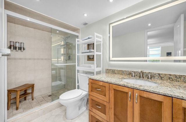 bathroom with tile patterned flooring, a shower with door, vanity, and toilet