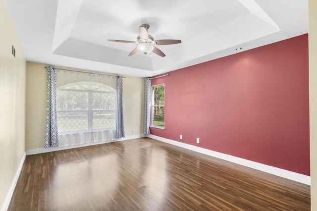 unfurnished room with a raised ceiling, ceiling fan, and hardwood / wood-style flooring