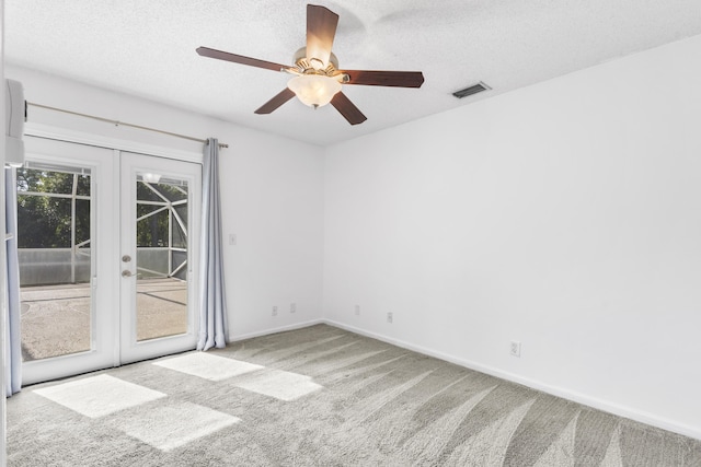 carpeted spare room featuring ceiling fan, french doors, and a textured ceiling