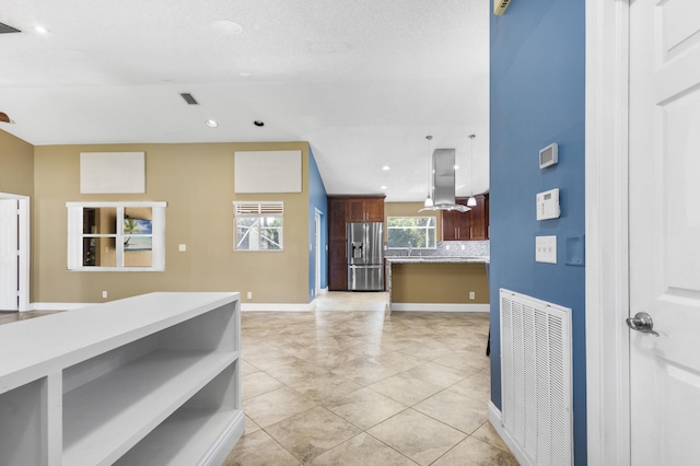 kitchen featuring decorative backsplash, stainless steel fridge, light tile patterned flooring, and island range hood