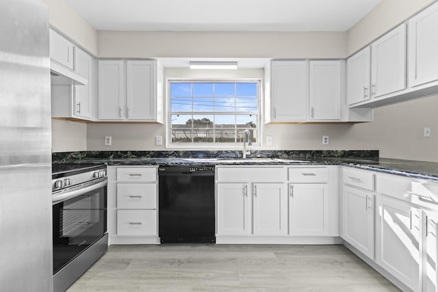 kitchen with appliances with stainless steel finishes, light hardwood / wood-style floors, white cabinetry, and dark stone countertops