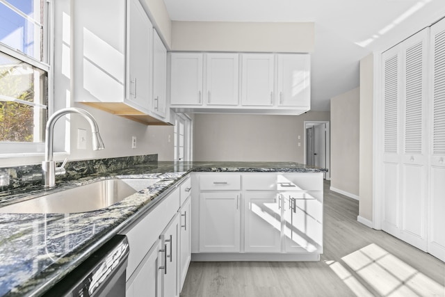 kitchen with dishwasher, dark stone countertops, white cabinetry, and sink