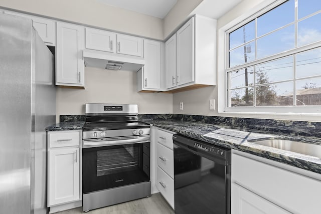 kitchen featuring dark stone countertops, white cabinetry, light hardwood / wood-style flooring, and stainless steel appliances