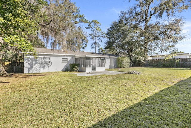 rear view of property with a yard, a patio area, and a sunroom