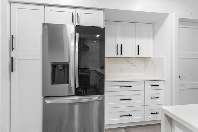 kitchen with white cabinets, decorative backsplash, and stainless steel fridge