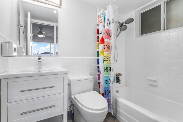 full bathroom featuring ceiling fan, toilet, shower / bath combo with shower curtain, vanity, and tile walls