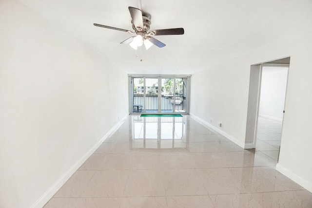 unfurnished room with ceiling fan and a wall of windows