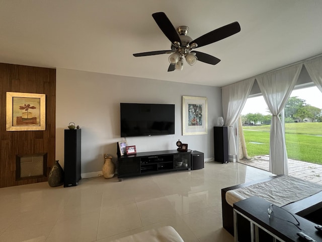 living room with ceiling fan, light tile patterned floors, and wooden walls