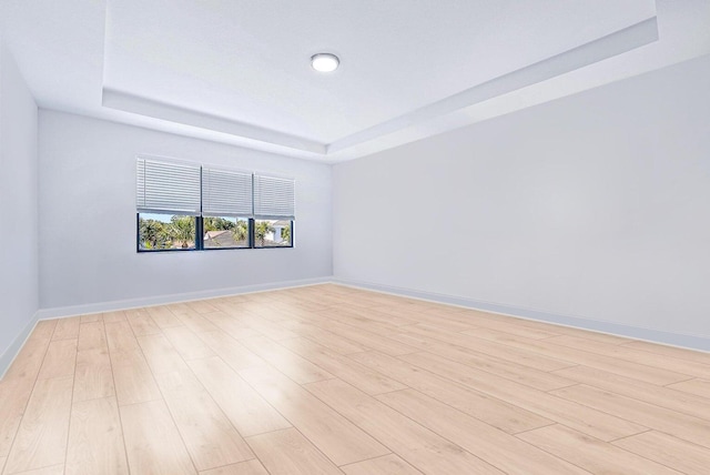 unfurnished room with light hardwood / wood-style flooring and a raised ceiling