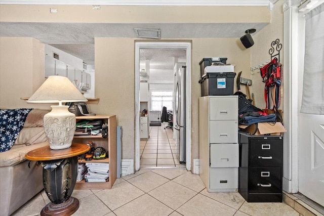 interior space with light tile patterned floors, a textured ceiling, and stainless steel refrigerator