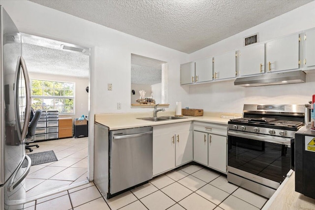 kitchen with light tile patterned floors, stainless steel appliances, white cabinetry, and sink