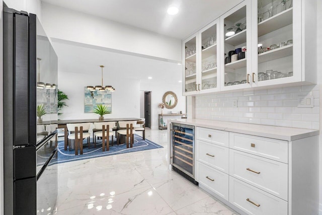 kitchen featuring light stone countertops, black fridge, beverage cooler, decorative light fixtures, and white cabinets