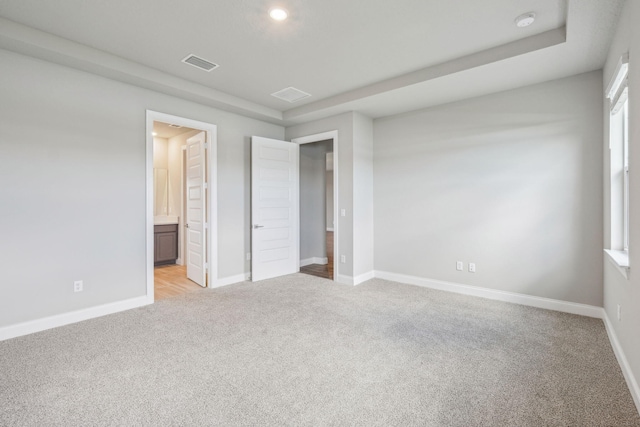 unfurnished bedroom featuring light carpet and connected bathroom