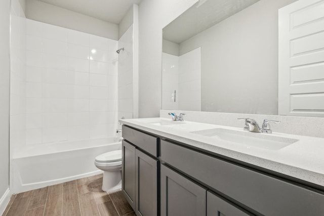 full bathroom with hardwood / wood-style flooring, tiled shower / bath, vanity, and toilet