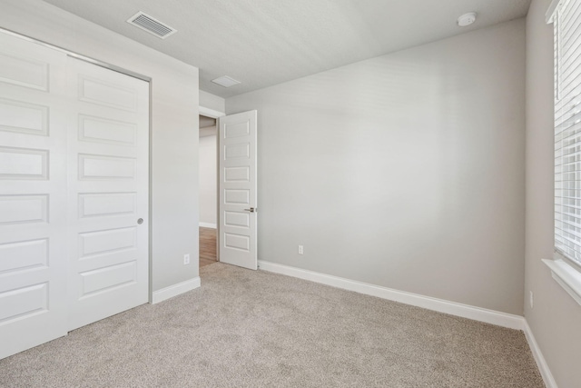 unfurnished bedroom with light carpet, multiple windows, and a closet