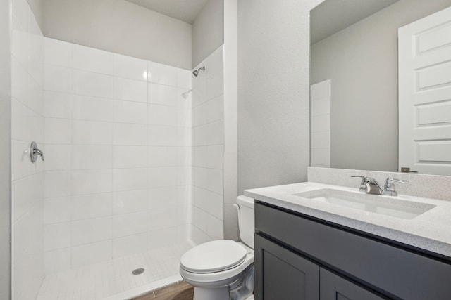 bathroom featuring tiled shower, vanity, and toilet