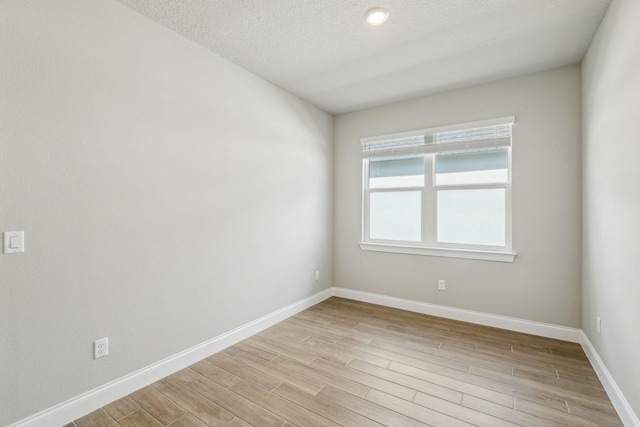 unfurnished room with a textured ceiling and light wood-type flooring