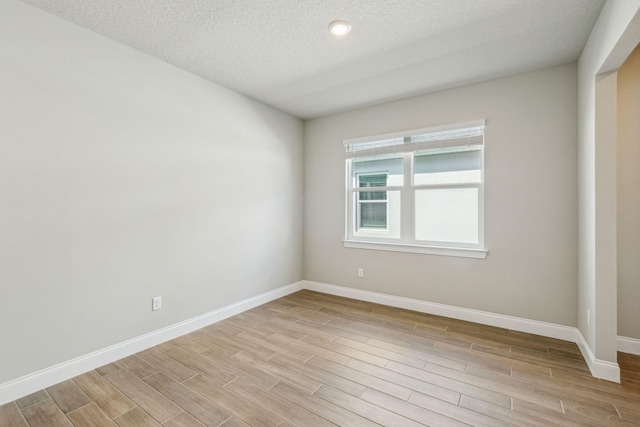 spare room with light hardwood / wood-style floors and a textured ceiling