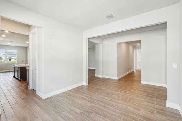 unfurnished room featuring sink and a textured ceiling