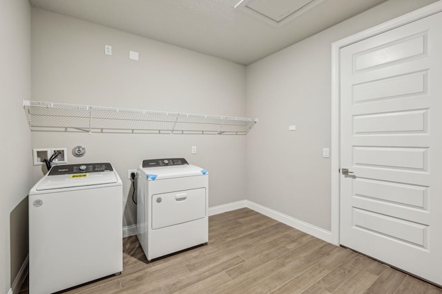 laundry area with separate washer and dryer and light hardwood / wood-style flooring