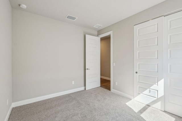 unfurnished bedroom with light colored carpet and a closet