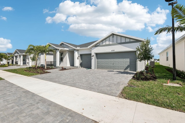 view of front of home with cooling unit, a garage, and a front lawn