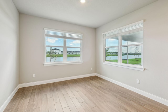 empty room featuring a water view and light hardwood / wood-style floors