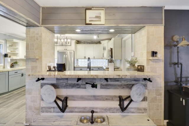 kitchen featuring stainless steel refrigerator, light hardwood / wood-style floors, pendant lighting, ceiling fan with notable chandelier, and backsplash