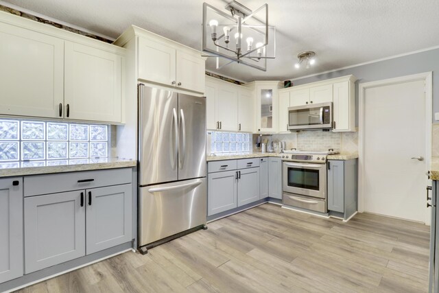 kitchen featuring stainless steel appliances, sink, light hardwood / wood-style floors, and decorative backsplash